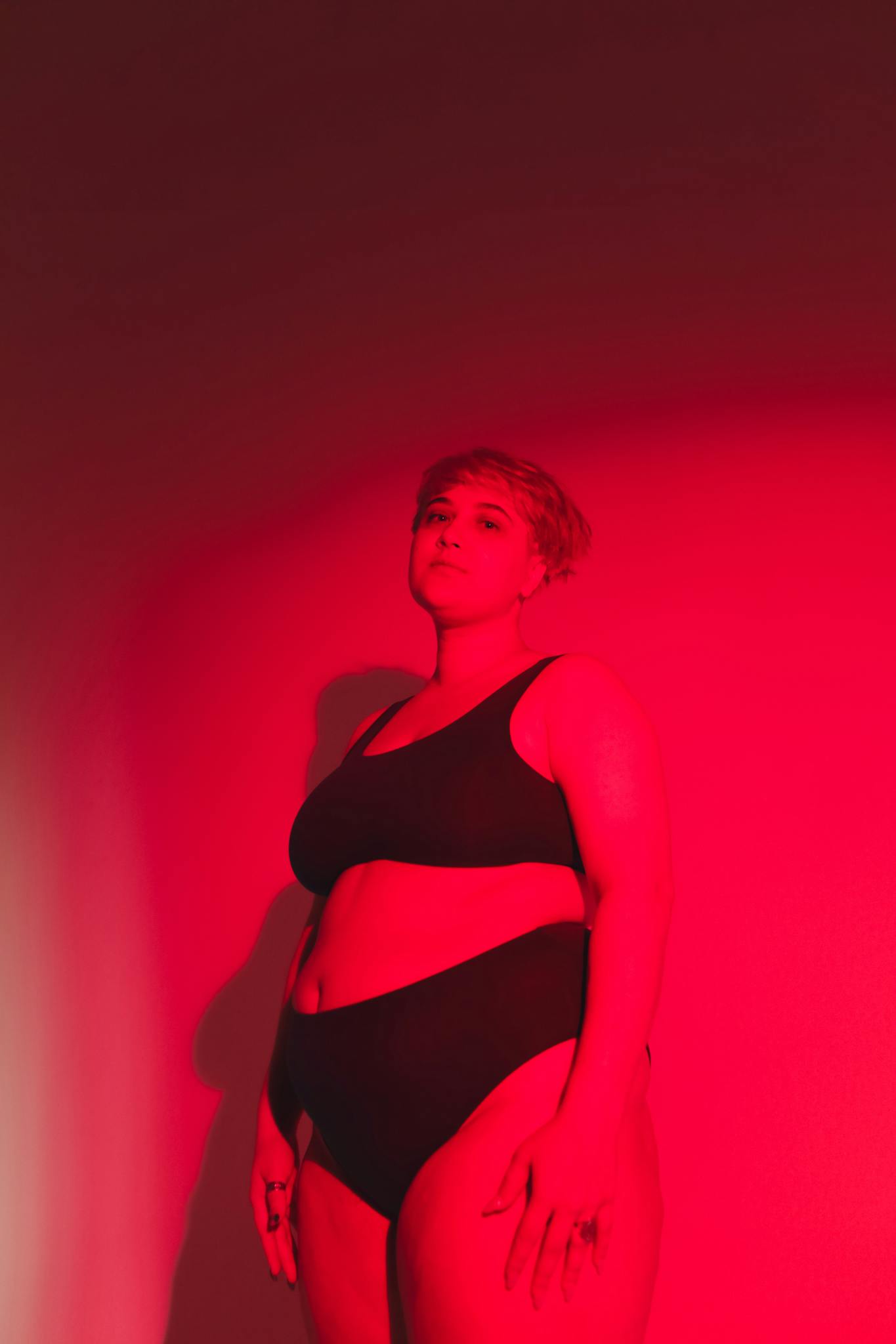 Empowering image of a plus size woman in moody red lighting, celebrating body positivity.