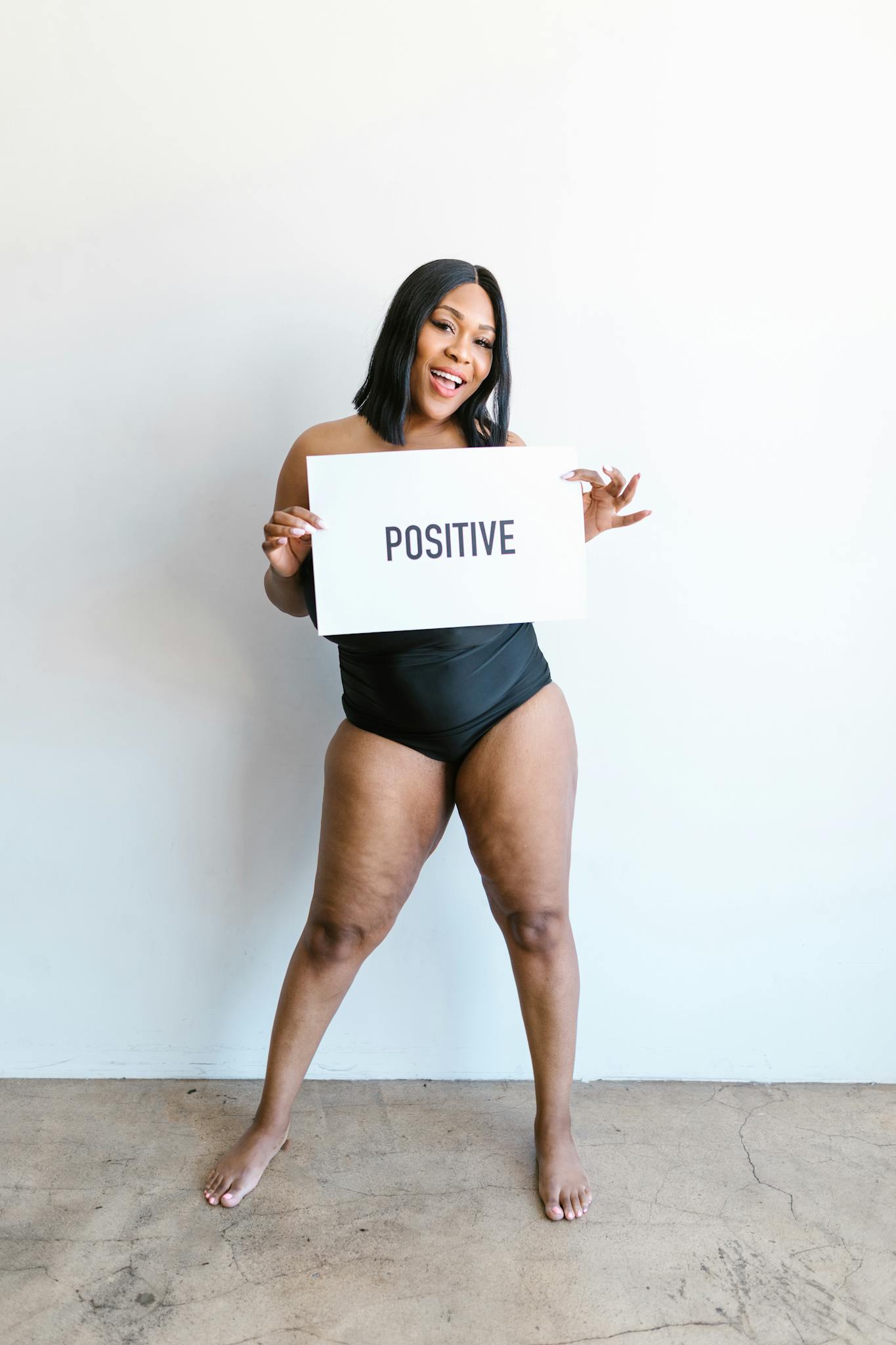 Empowering portrait of a body positive woman in swimwear holding a sign indoors.
